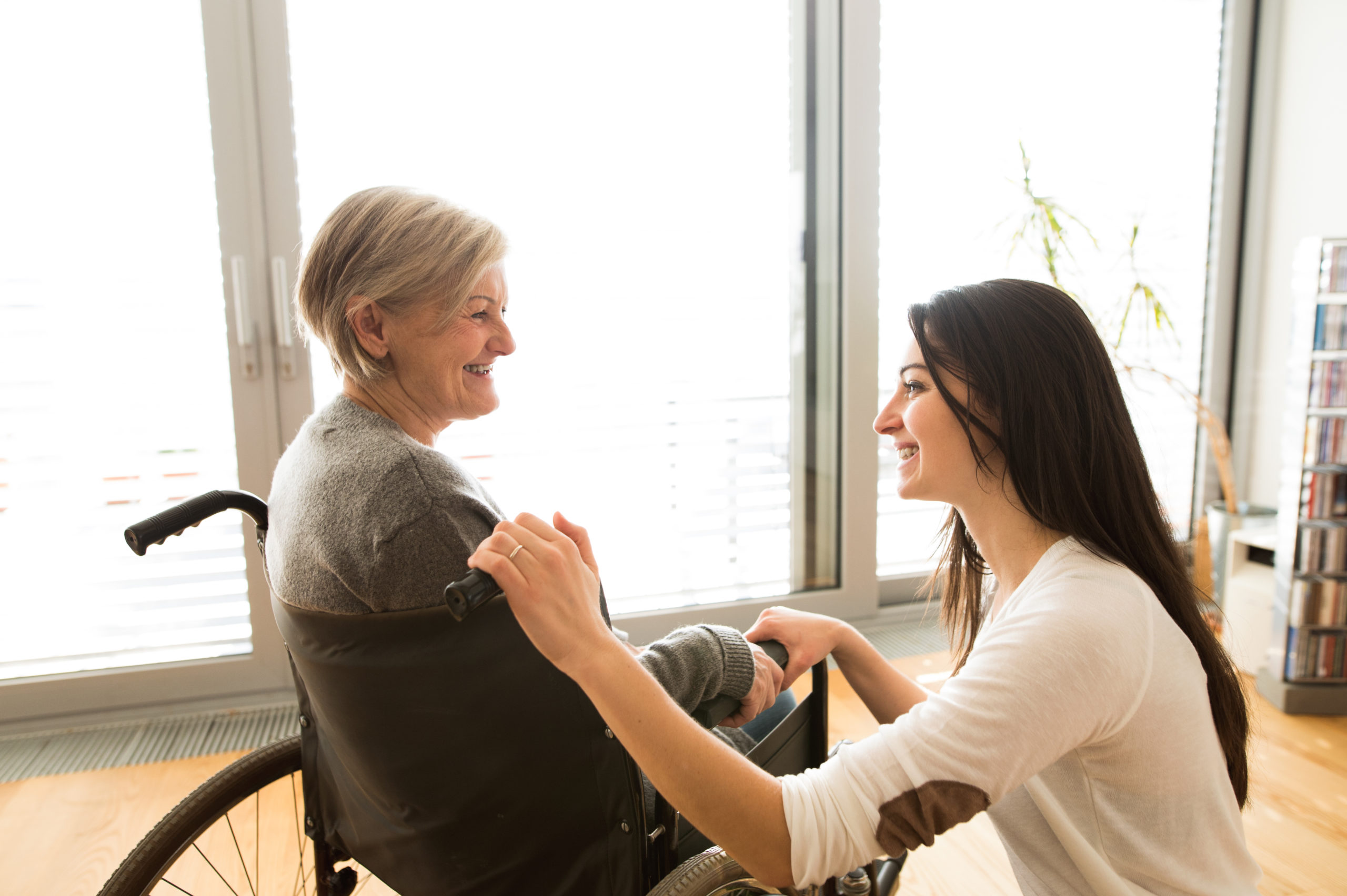 graphicstock disabled senior woman in wheelchair at home in her living room with her young daughter caring for her_SdM7iNOLzZ scaled 1